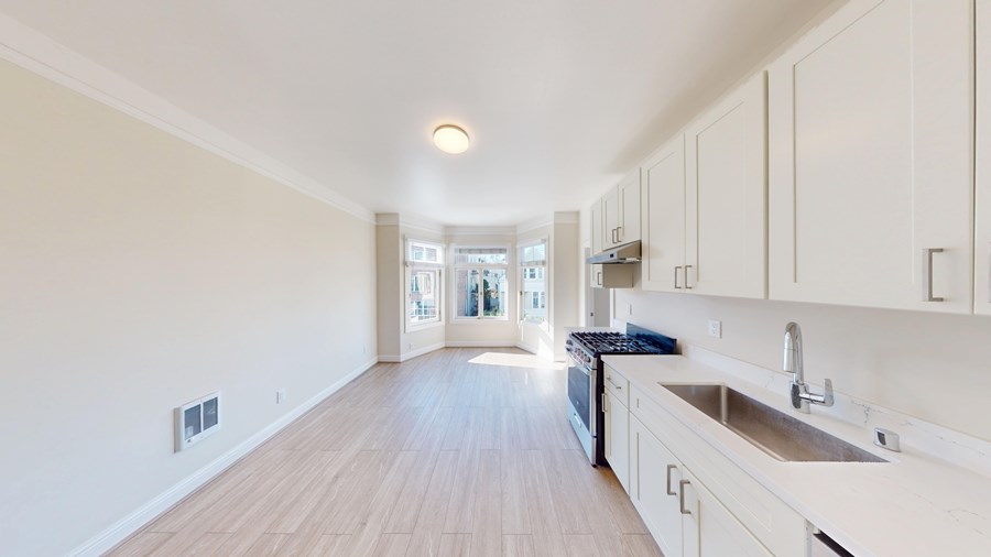 A kitchen with white cabinets and a wooden floor.